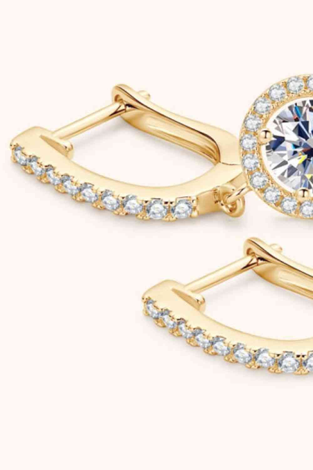 a pair of gold earrings with a white diamond