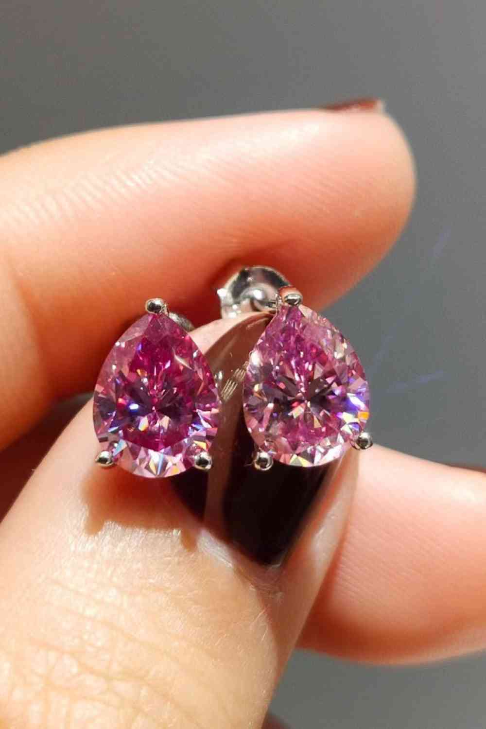 a pair of pink diamond earrings on someone's finger