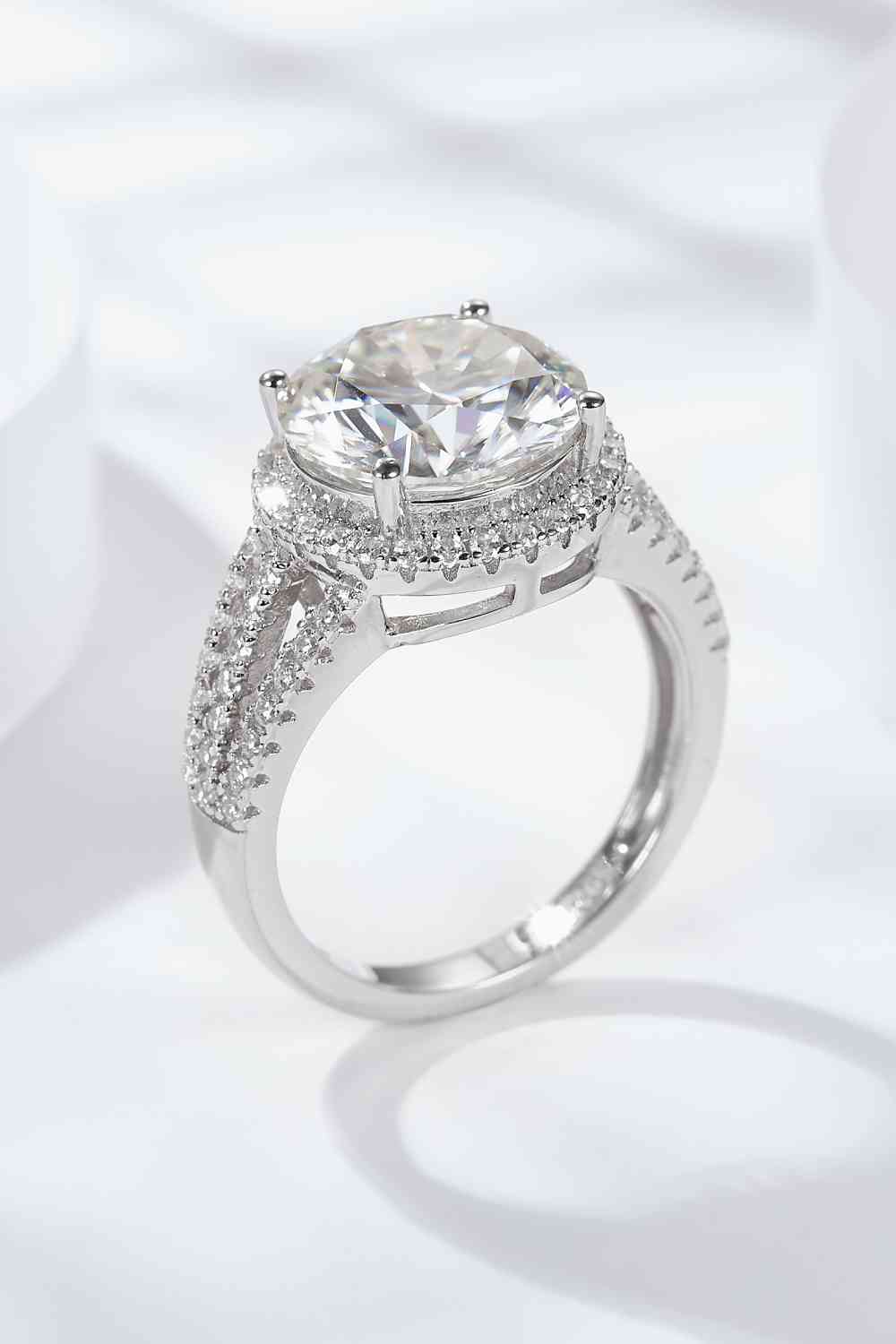 a white gold ring with a cushion cut diamond surrounded by pave diamonds