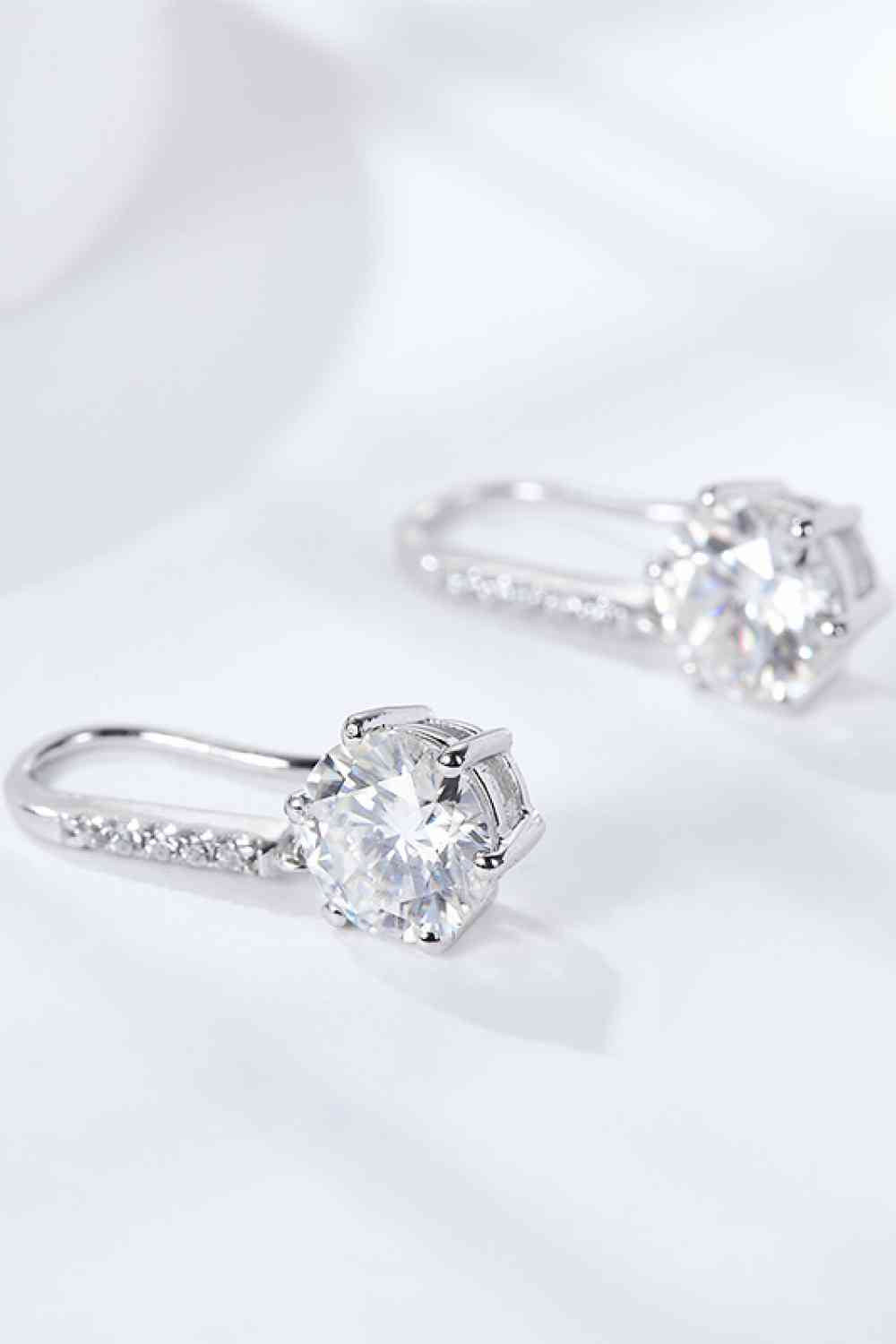 a pair of diamond earrings on a white surface