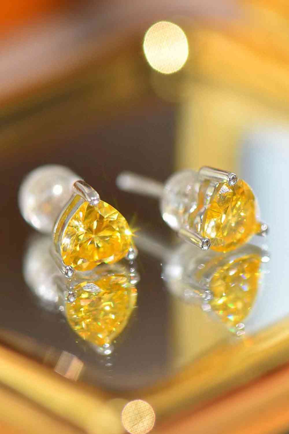a pair of yellow diamond earrings sitting on top of a mirror