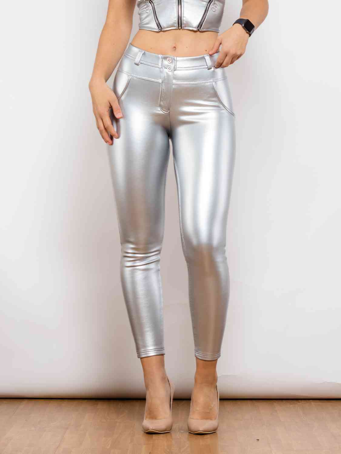 a woman wearing silver pants and a crop top