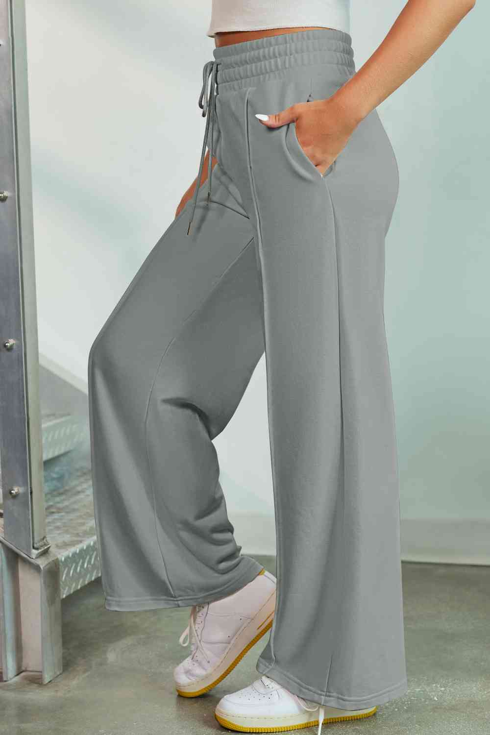 a woman wearing grey pants and a white tank top