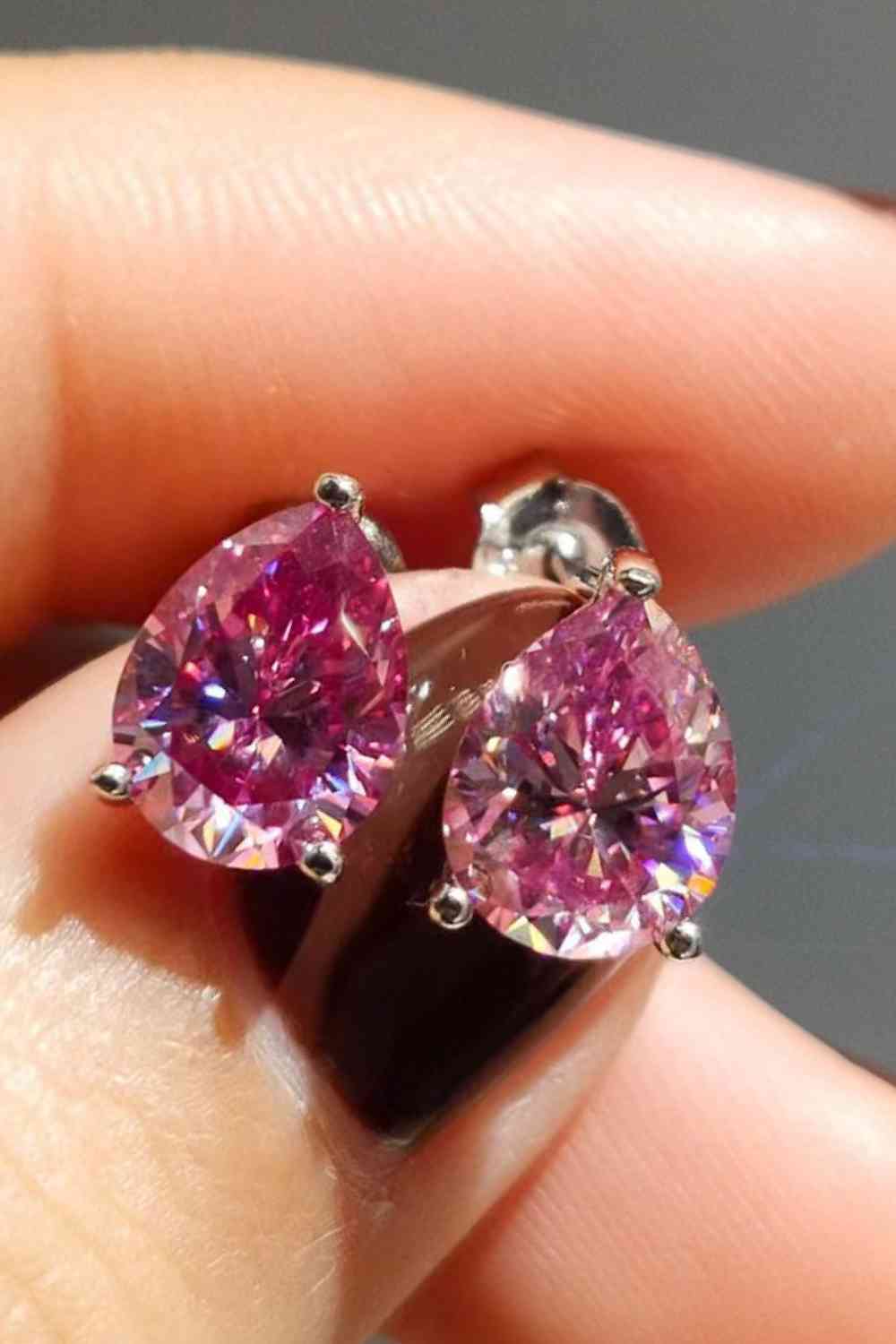 a pair of pink diamond earrings on a person's finger
