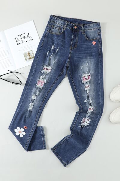 a pair of ripped jeans with flowers on them