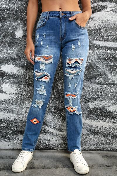 a woman standing in front of a wall wearing ripped jeans