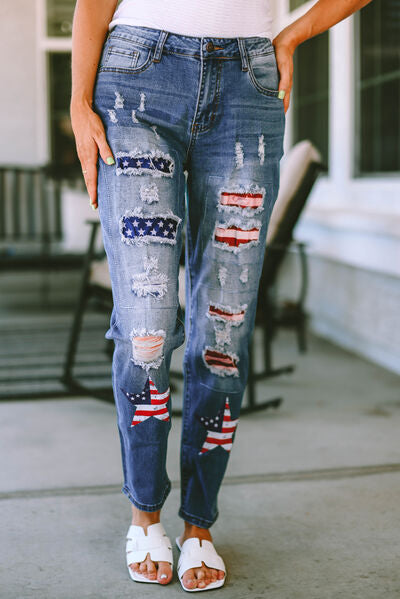 a woman standing on a sidewalk wearing ripped jeans with american flags on them