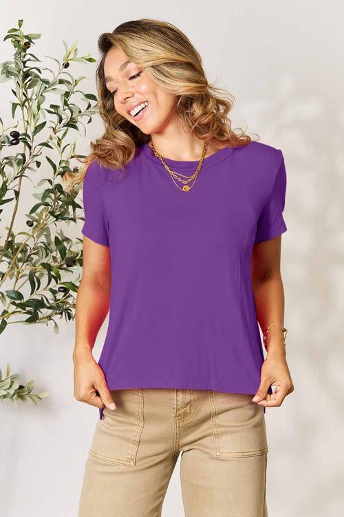 a woman wearing a purple top and tan pants