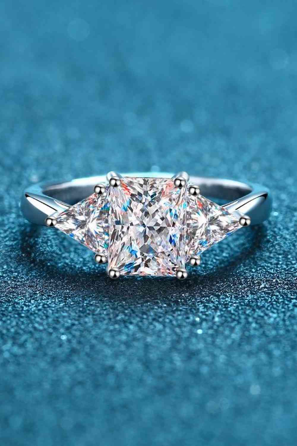 a three stone diamond ring on a blue surface