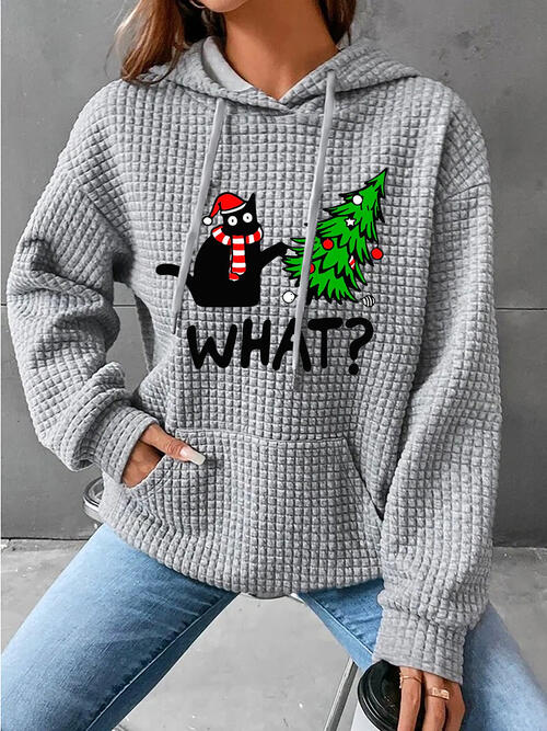 a woman wearing a grey sweater with a christmas tree on it