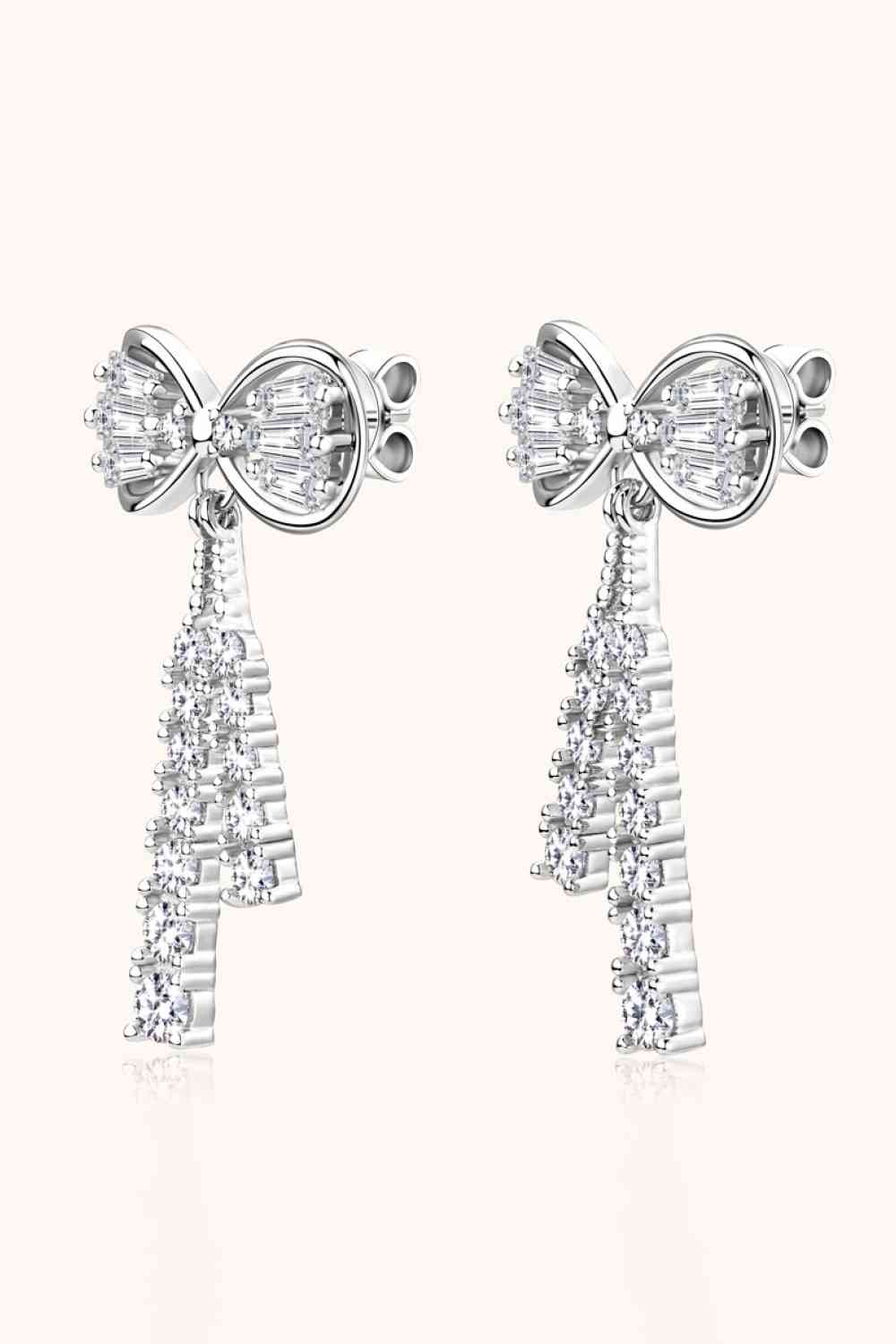 a pair of earrings with a bow and crystal stones
