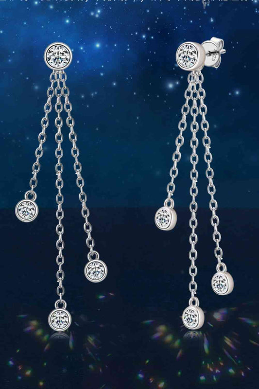 a pair of dangling earrings with a star in the background