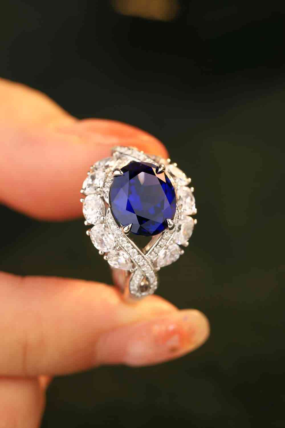 a woman's hand holding a blue sapphire and diamond ring