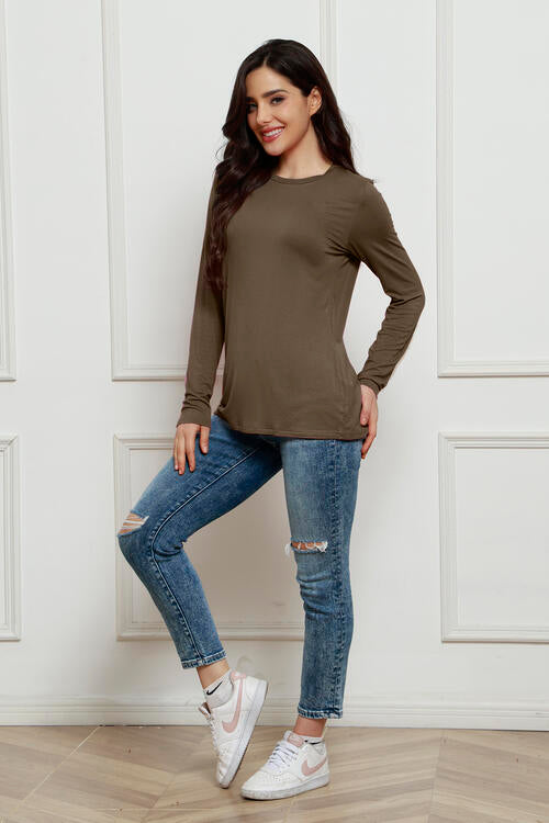 a woman standing on a wooden floor wearing ripped jeans