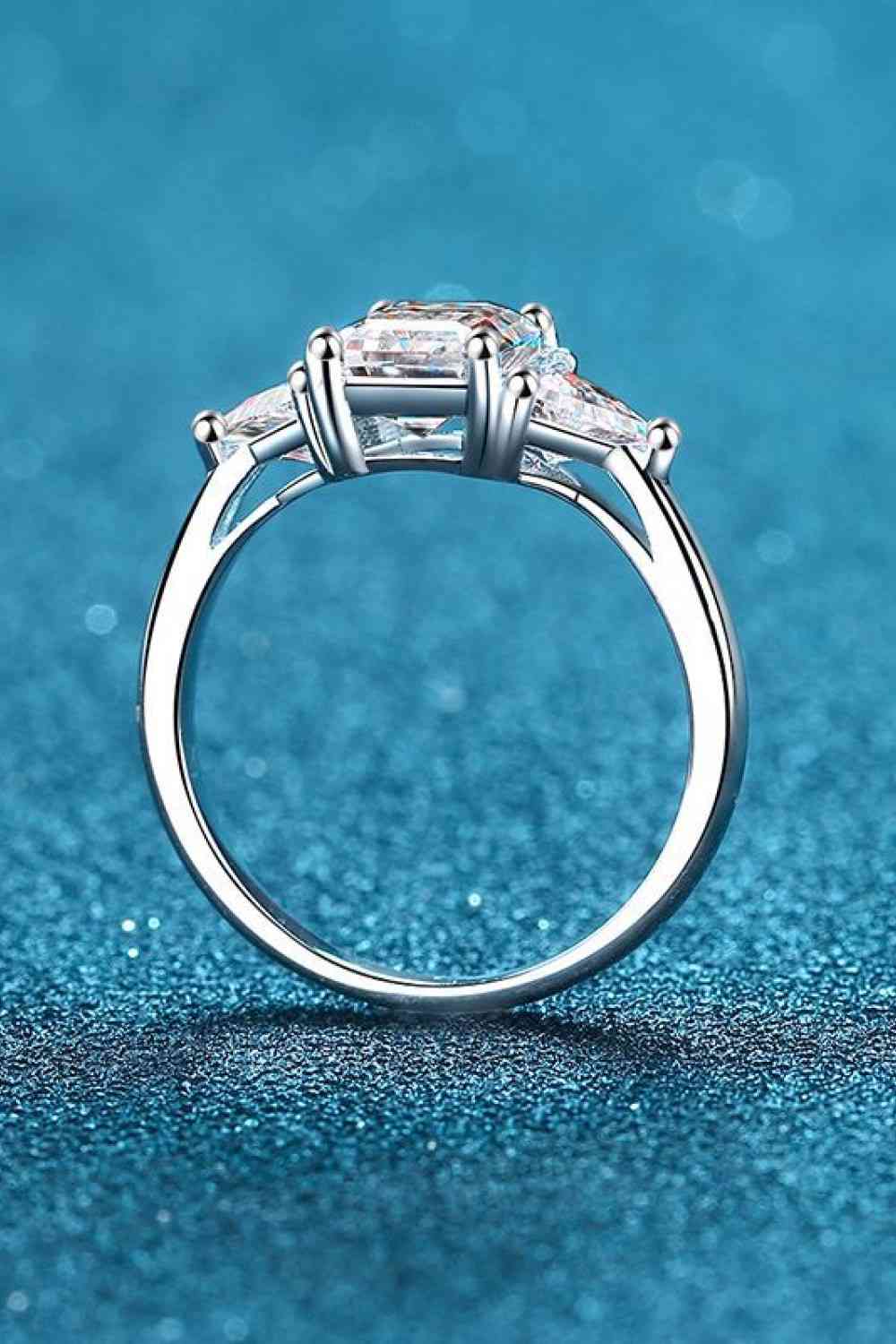 a three stone diamond ring on a blue background