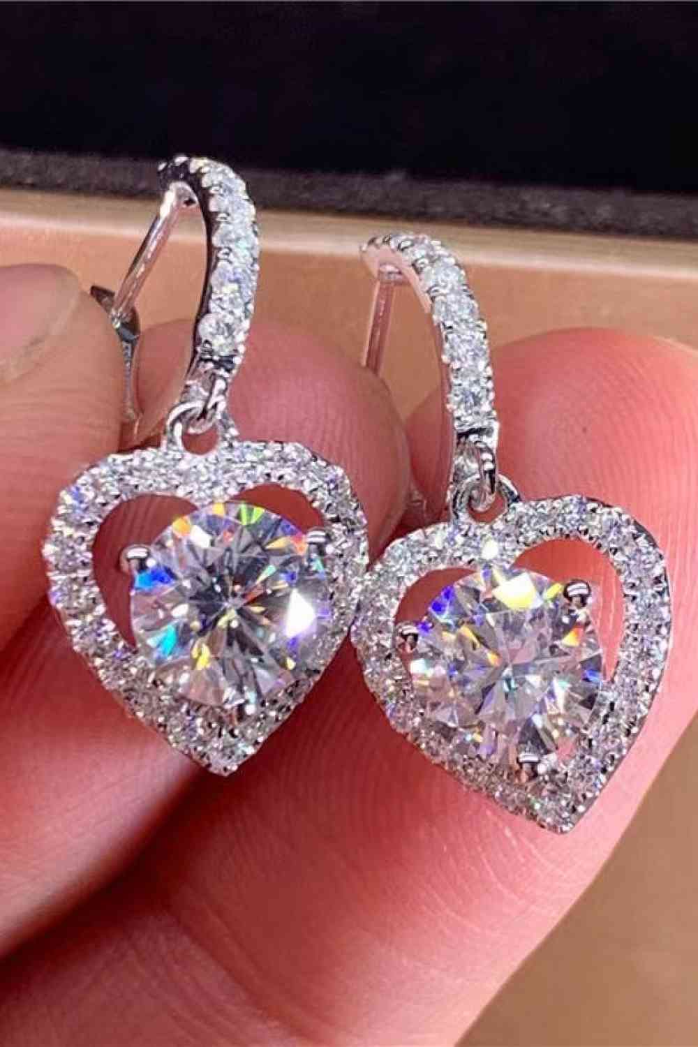 a person holding a pair of heart shaped earrings