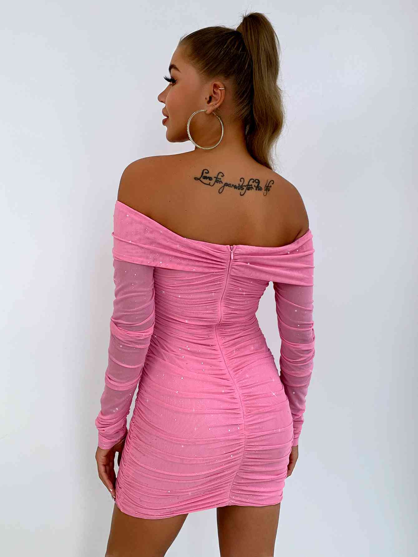 a woman in a pink dress with tattoos on her back