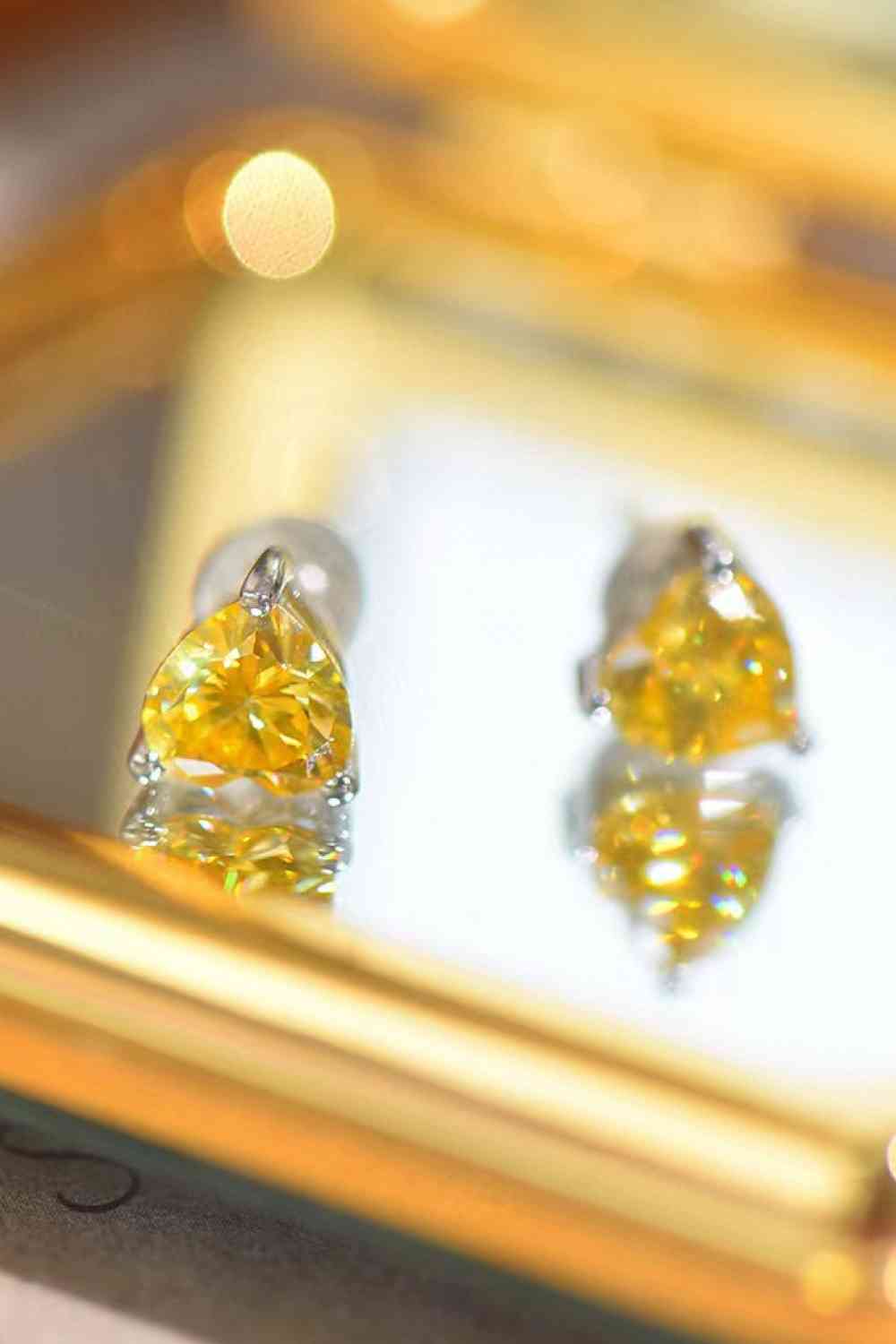 a pair of yellow diamond earrings sitting on top of a mirror