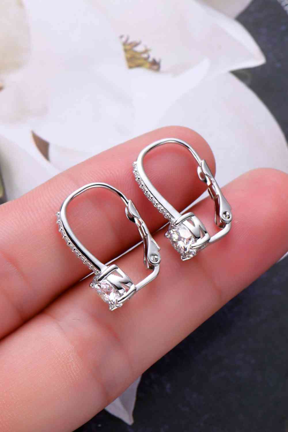 a pair of silver earrings on a person's hand