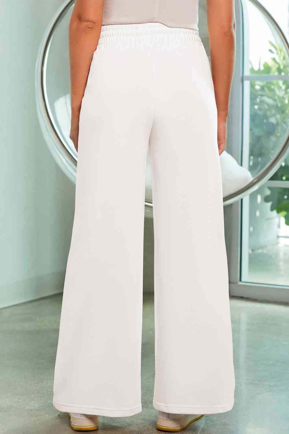 a woman in white pants standing in front of a mirror