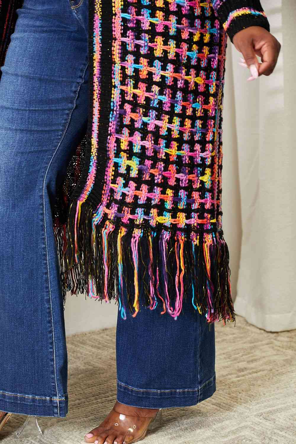 a woman is wearing a multicolored sweater and jeans