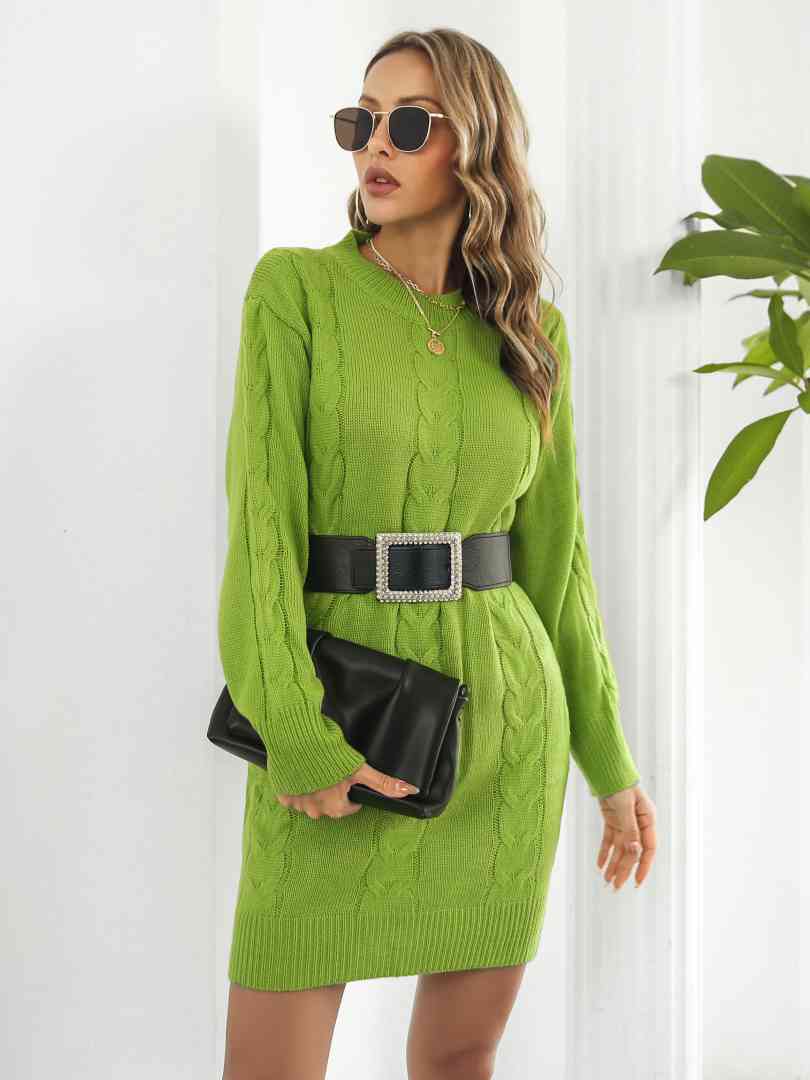 a woman in a green sweater dress and black purse