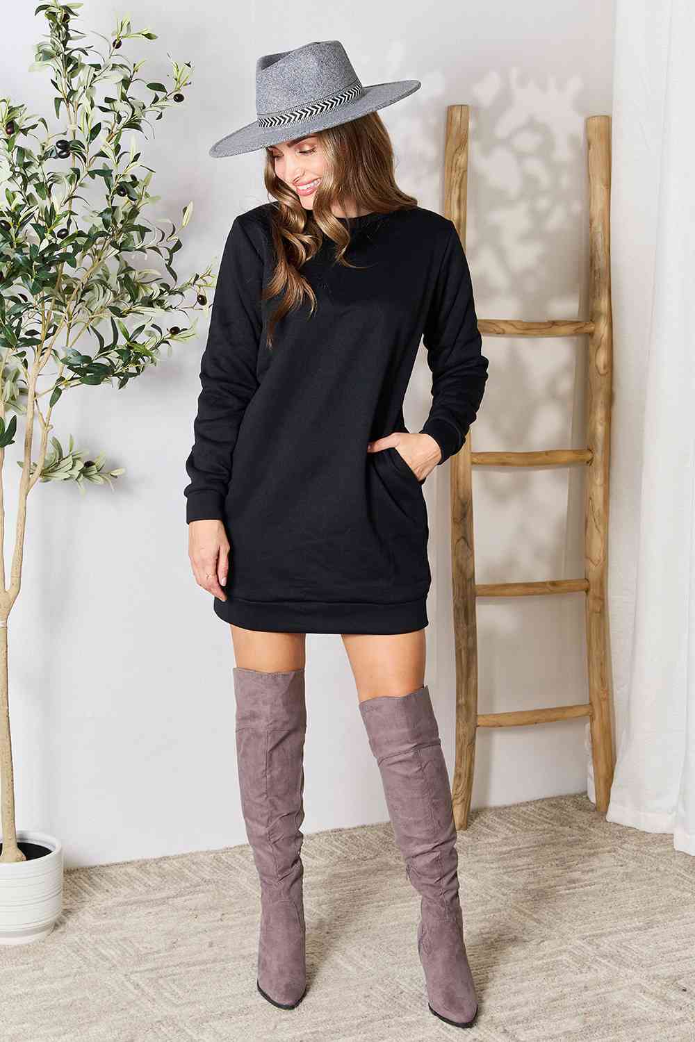a woman wearing a black sweater dress and over the knee boots
