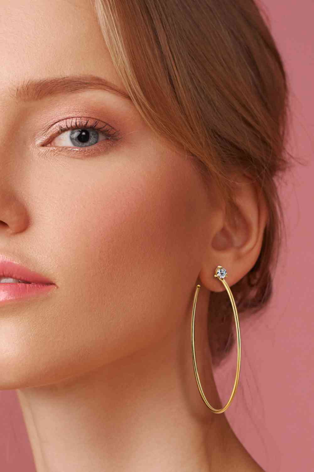 a woman wearing a pair of gold hoop earrings