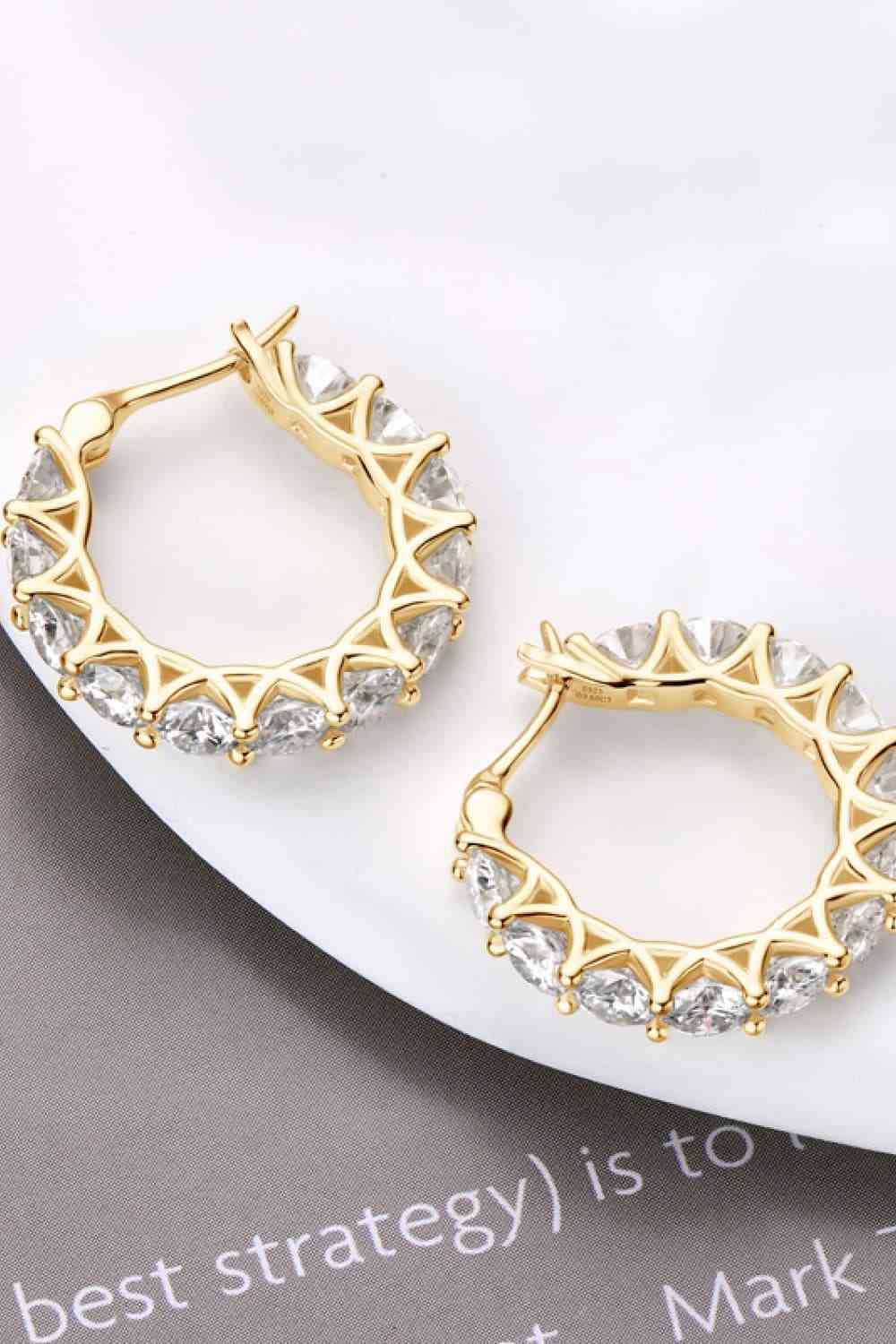 a pair of gold hoop earrings on a white plate