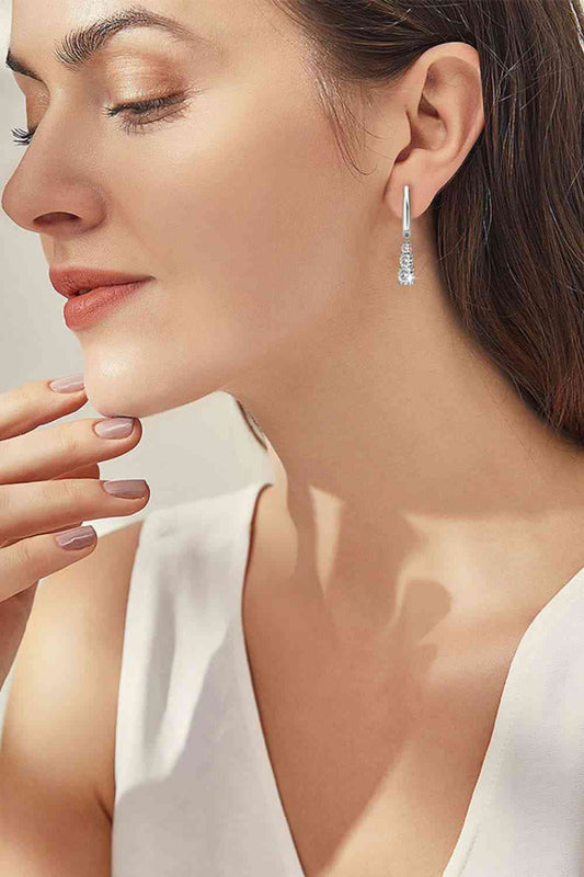 a woman wearing a pair of earrings and a white top