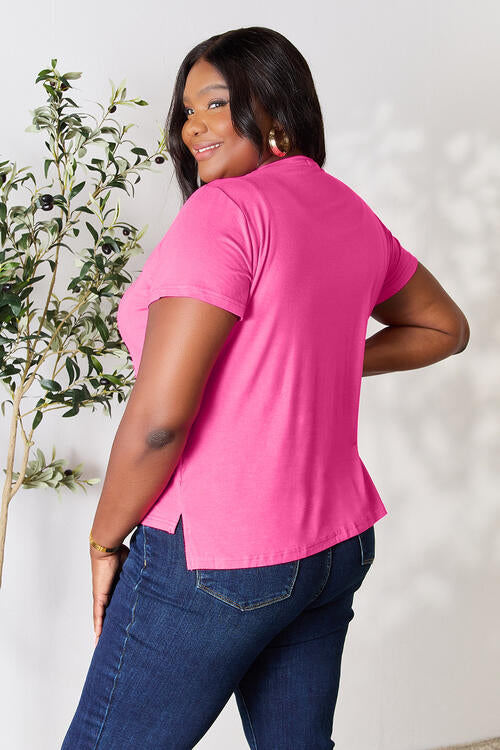 a woman in a pink shirt standing next to a tree
