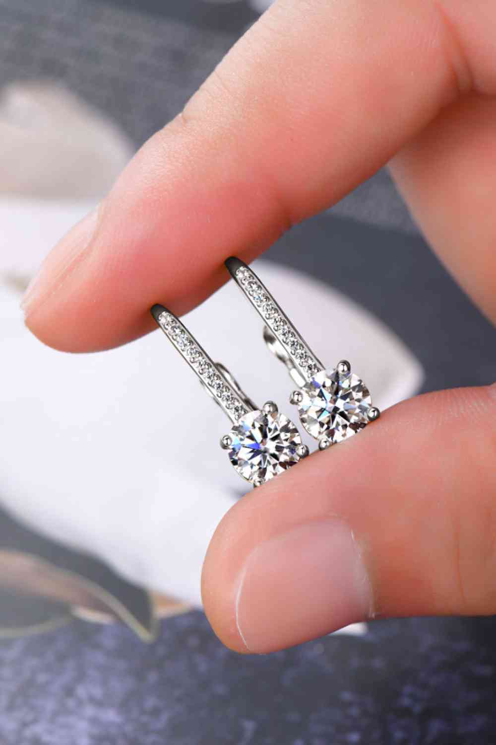 a person holding a pair of diamond earrings