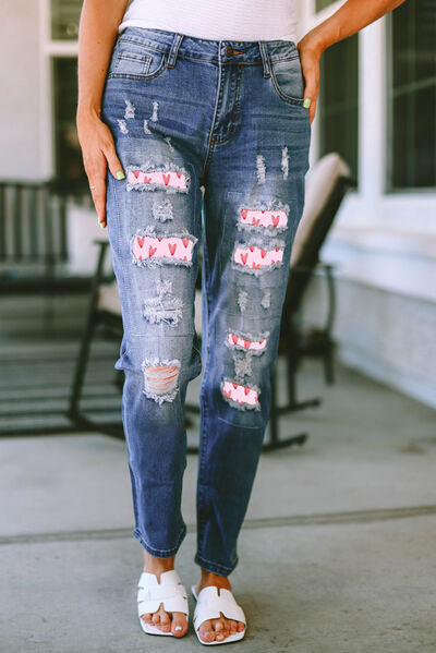 a woman standing on a sidewalk wearing ripped jeans