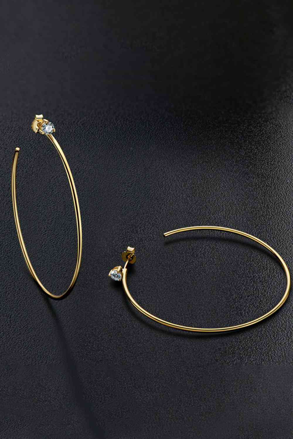 a pair of gold hoop earrings on a black surface