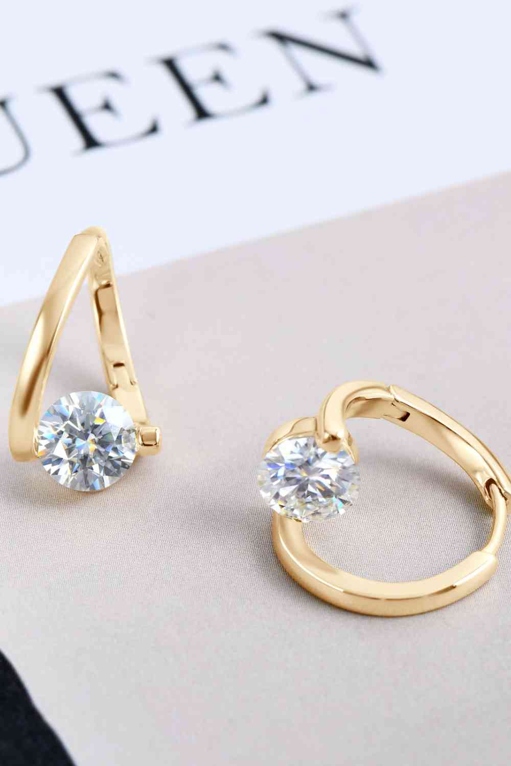 a pair of gold earrings with a diamond in the middle